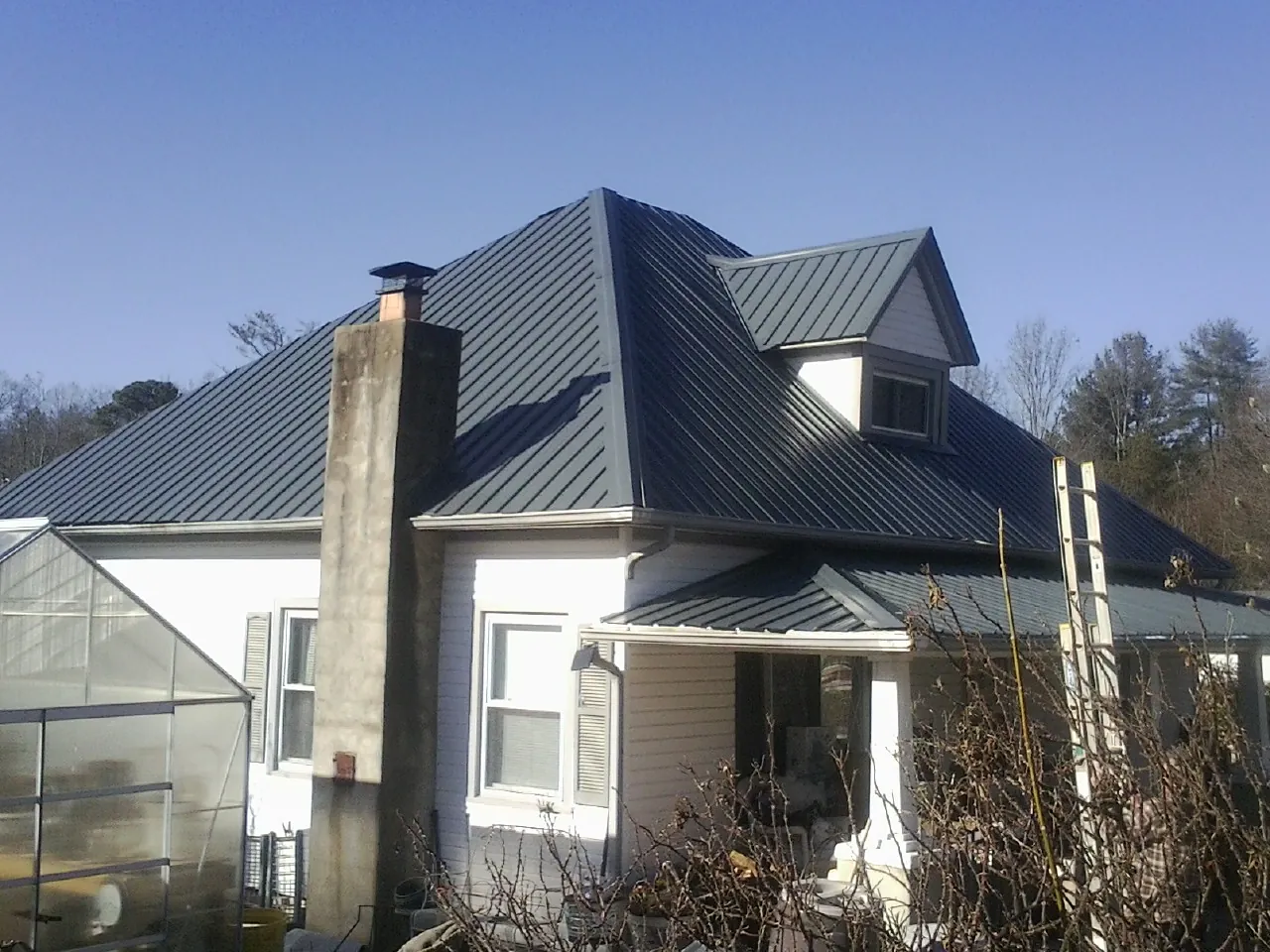 Dark blue standing seam metal roof on a white farmhouse with dormer — Slate & Tile Roof Repair by Roofing Brothers in Issaquah