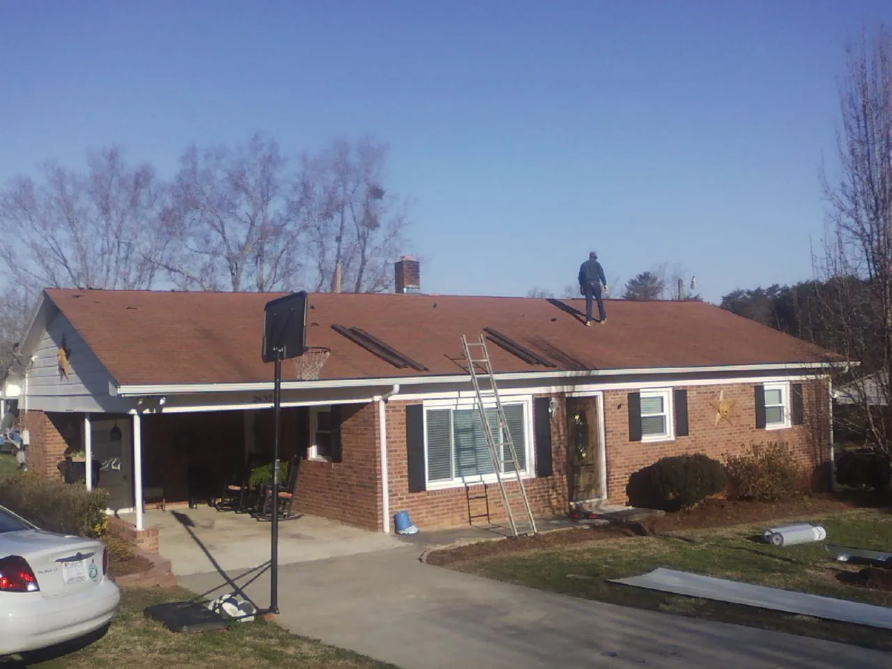Roofer stripping a shingle roof on a brick ranch before metal panels in Issaquah