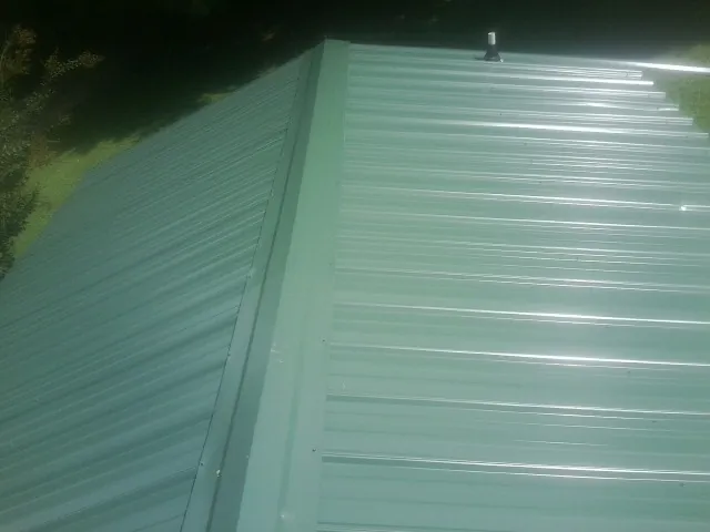 New green metal panels meeting at the ridge of a roof — Flat Roof Repair work by our crew in Issaquah