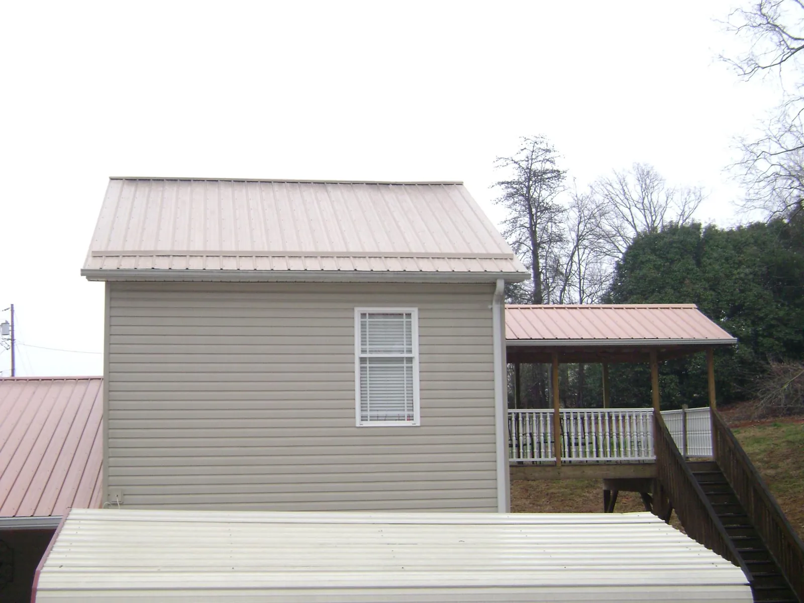 Tan metal roofs on a two story addition and attached porch, from a Roof Replacement job in Issaquah