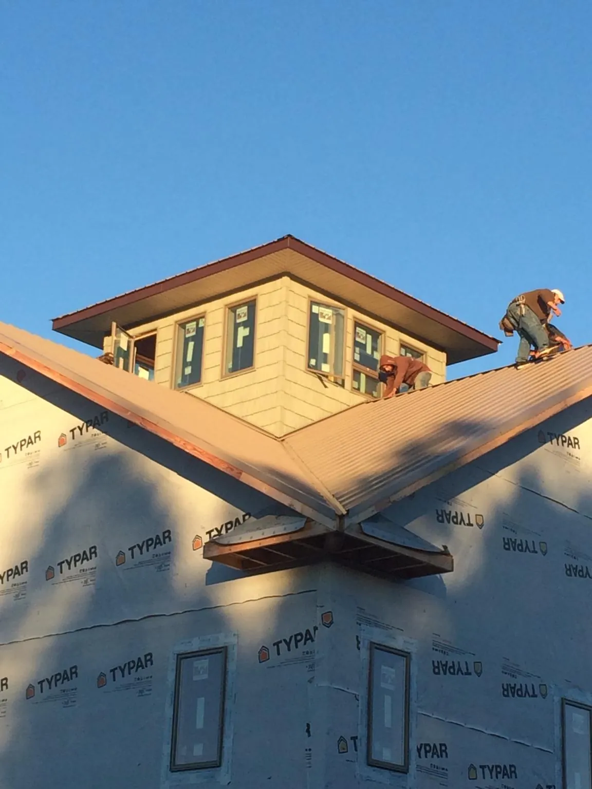Roofers working around a rooftop cupola on a new metal roof at sunset — Roof Waterproofing in Issaquah by Roofing Brothers